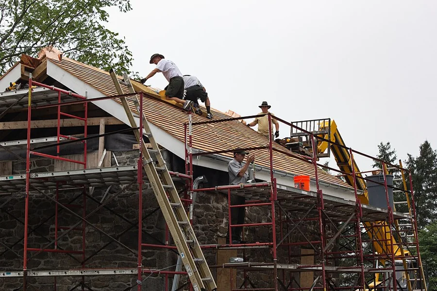 New roof decking being installed over a stone house